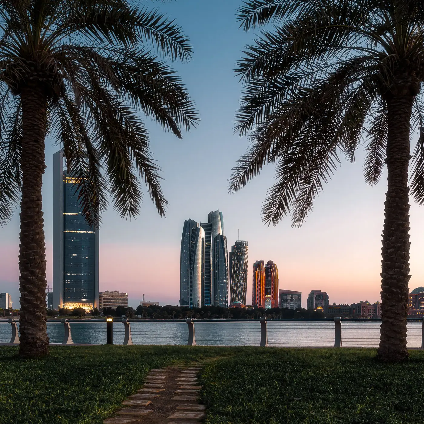 Abu Dhabi skyline framed by palm trees at dusk