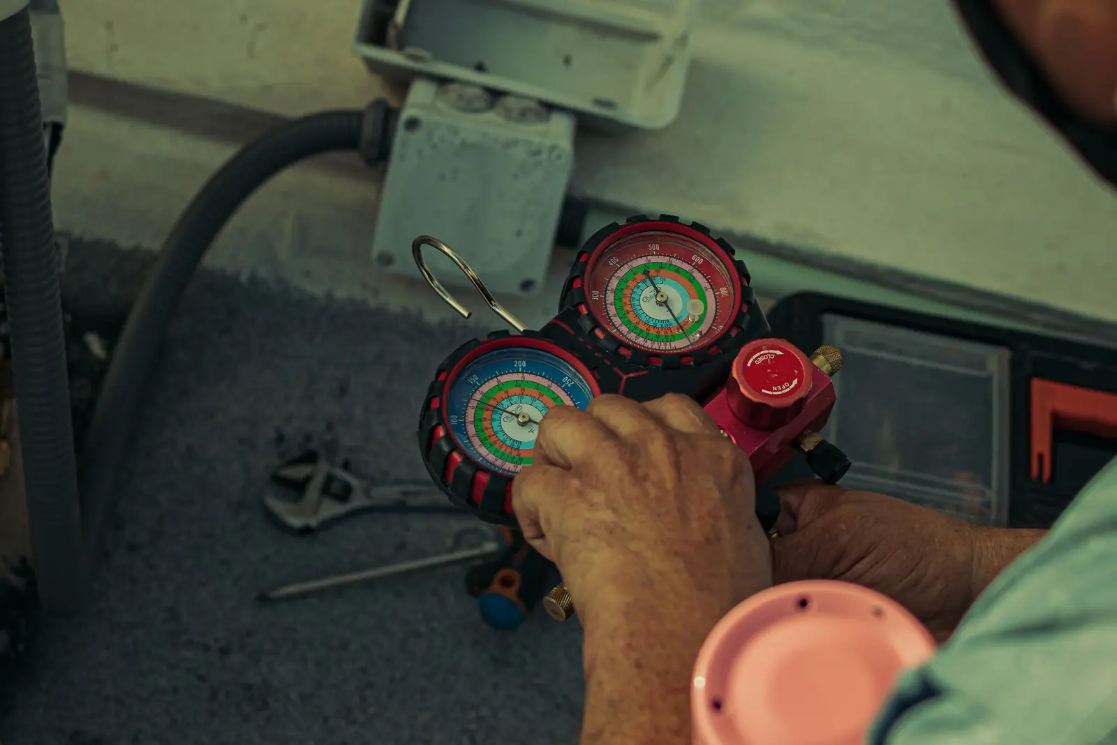 Technician checking refrigerant pressure with manifold gauges